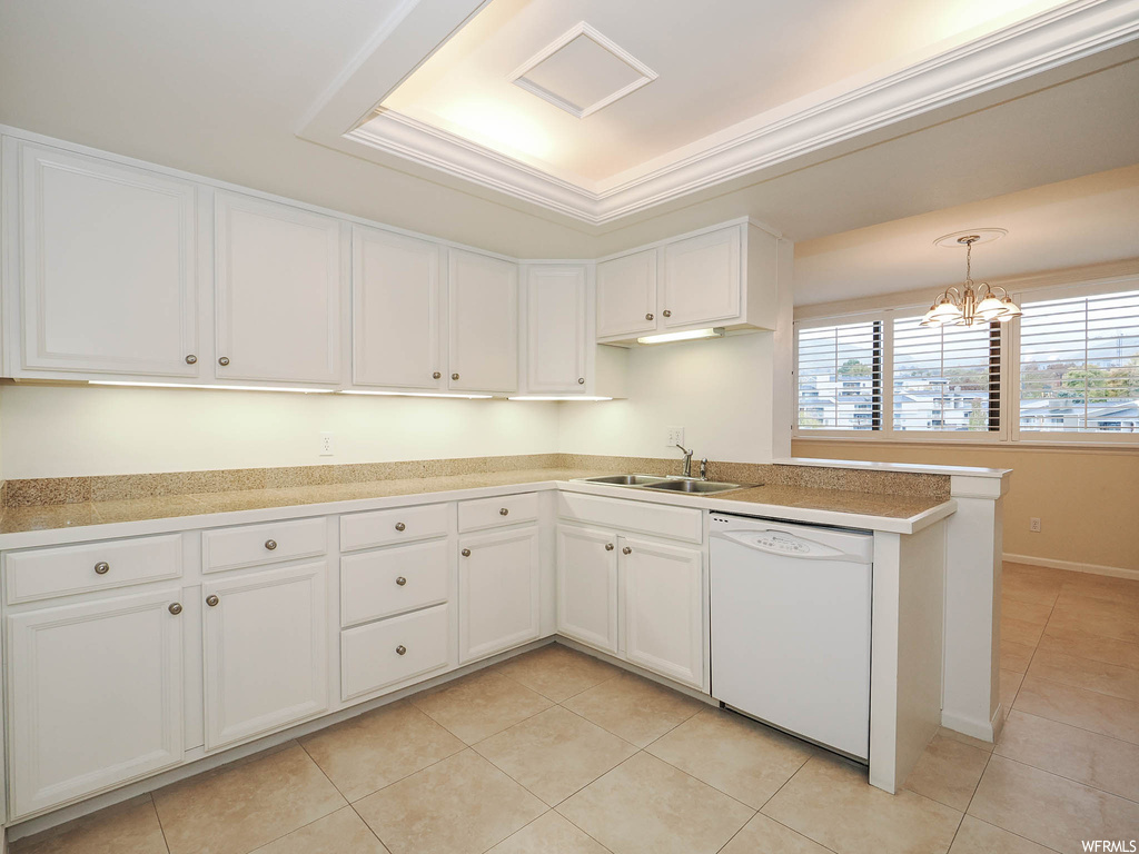 Kitchen featuring pendant lighting, an inviting chandelier, dishwasher, a tray ceiling, and white cabinetry