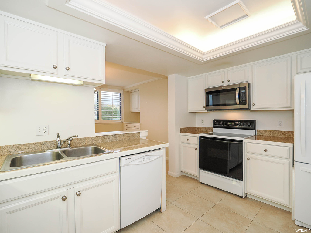 Kitchen with white appliances, white cabinets, and sink