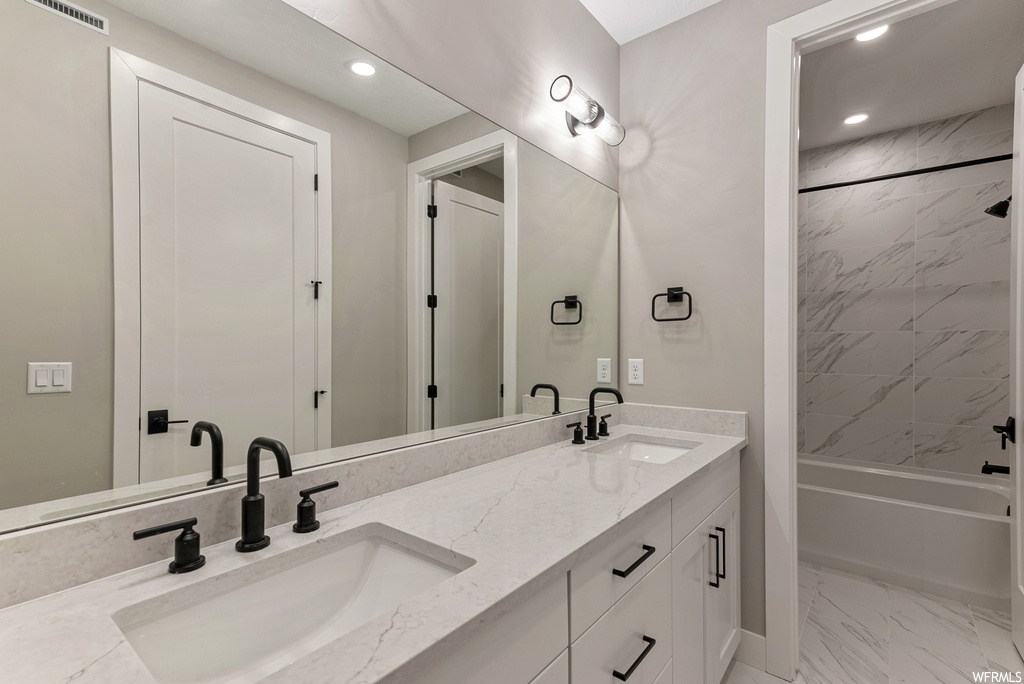 Bathroom with double sink, tiled shower / bath combo, oversized vanity, and tile flooring