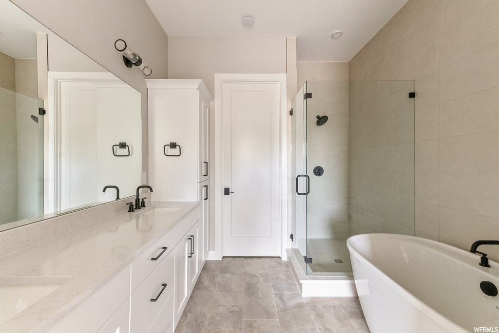 Bathroom with plus walk in shower, tile floors, tile walls, and dual bowl vanity