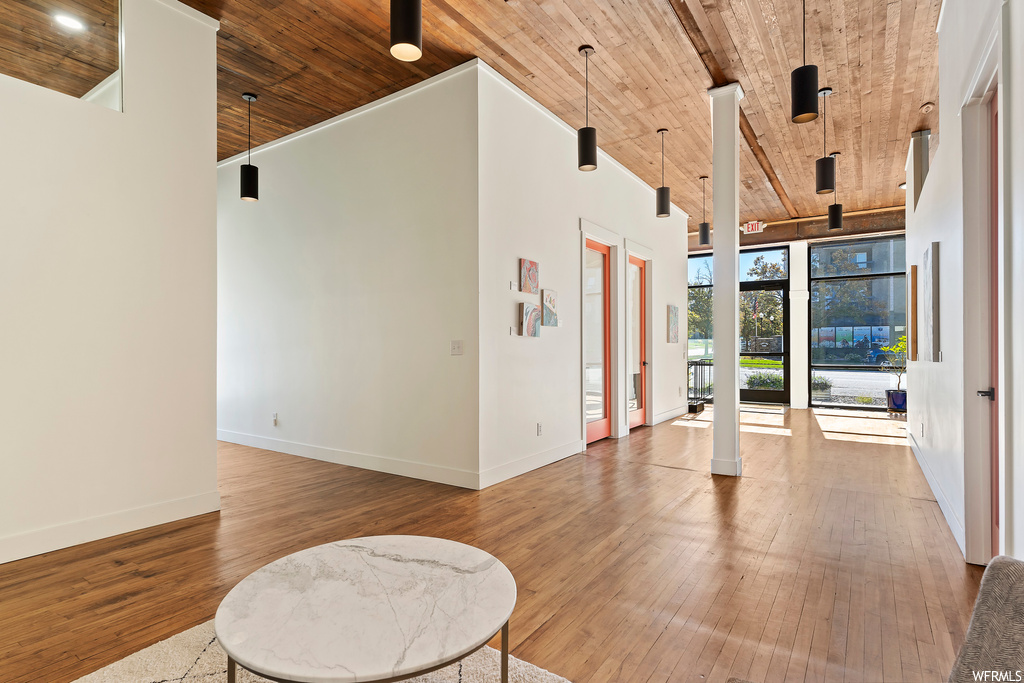 Unfurnished room with a wall of windows, wooden ceiling, a high ceiling, and light hardwood / wood-style floors