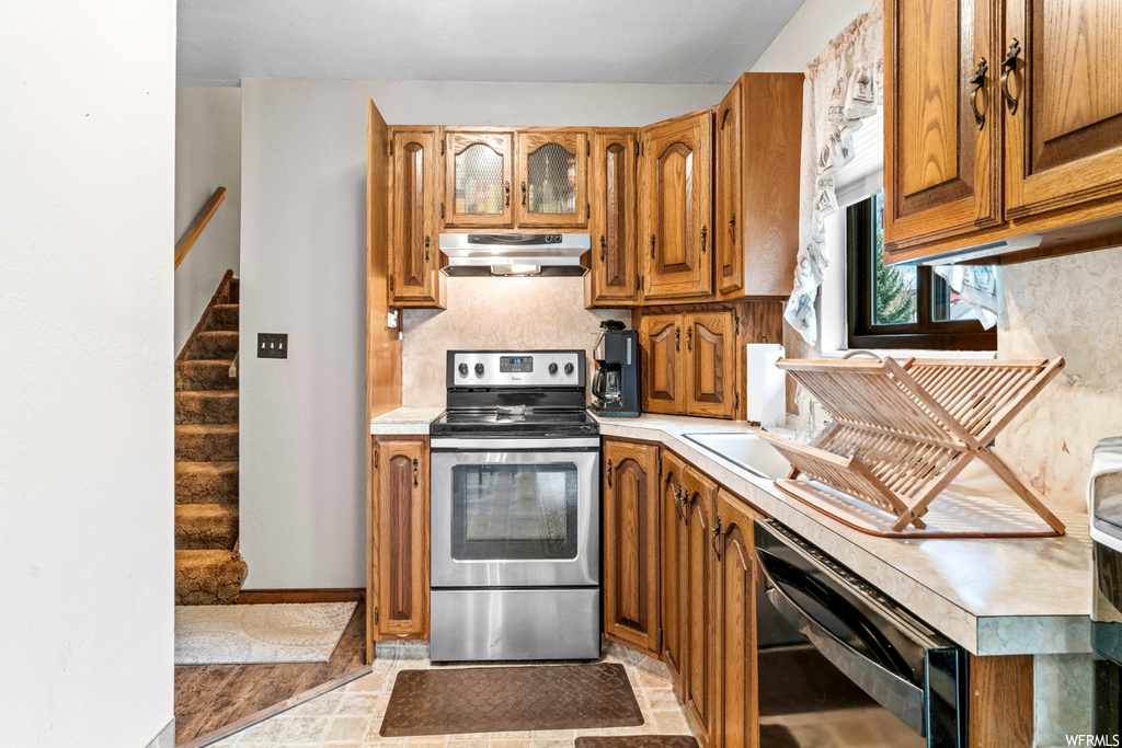 Kitchen featuring stainless steel electric range, black dishwasher, and light tile floors