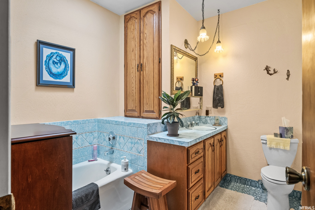 Bathroom featuring toilet, tile floors, large vanity, and a washtub