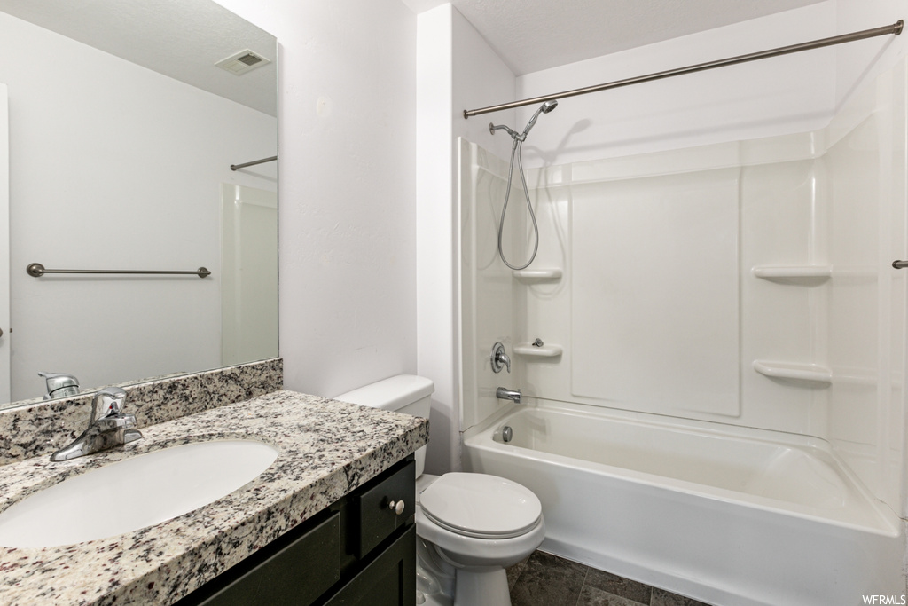 Full bathroom featuring toilet, tile flooring, washtub / shower combination, and vanity