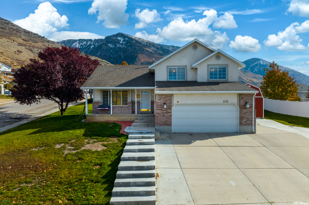 View of front facade featuring a garage, a front yard, and a mountain view