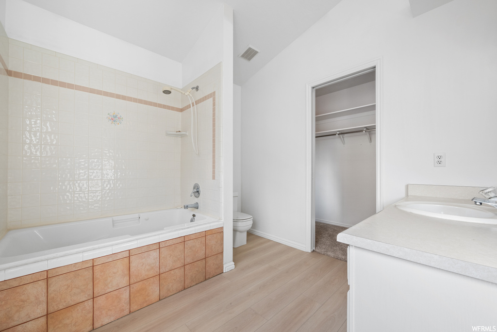 Full bathroom featuring toilet, vanity, tiled shower / bath combo, and hardwood / wood-style flooring