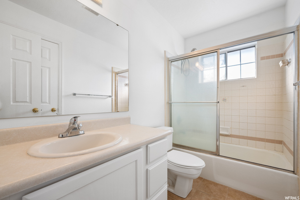 Full bathroom with toilet, tile flooring, enclosed tub / shower combo, and vanity