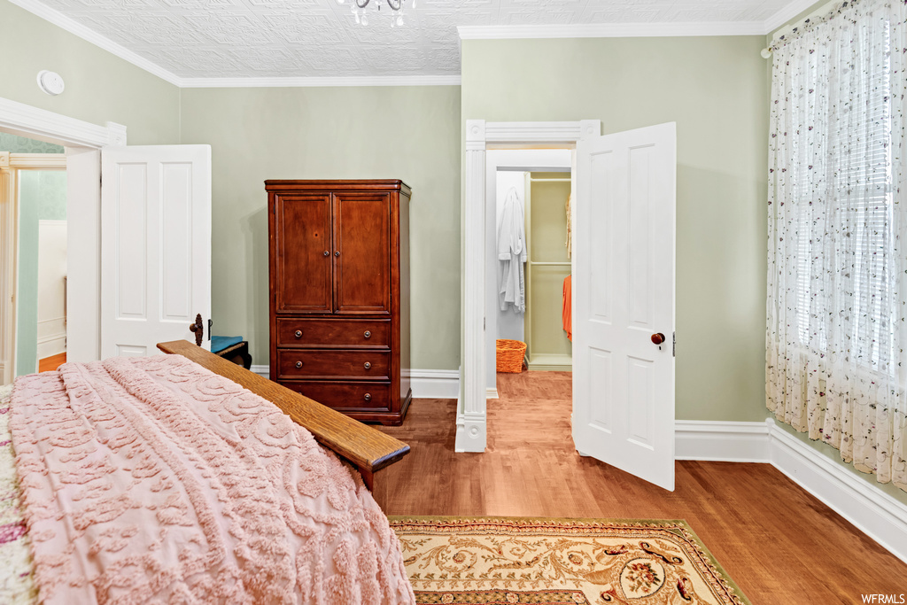 Bedroom featuring ornamental molding, decorative columns, and light hardwood / wood-style floors