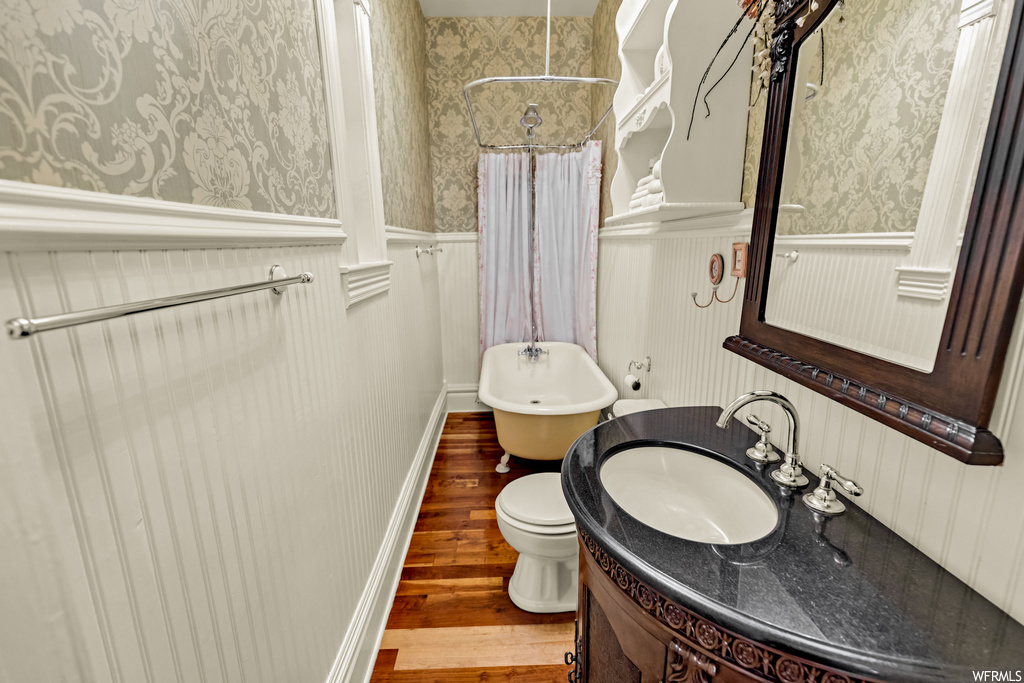 Bathroom featuring toilet, vanity with extensive cabinet space, and hardwood / wood-style floors