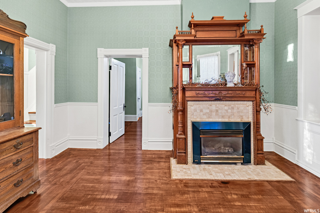 Living room with dark hardwood / wood-style flooring, a tiled fireplace, and ornamental molding