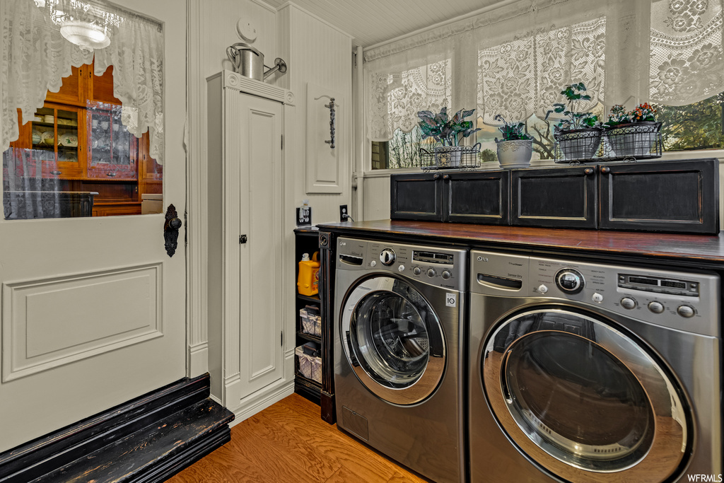 Washroom with washer and clothes dryer, cabinets, and light hardwood / wood-style flooring