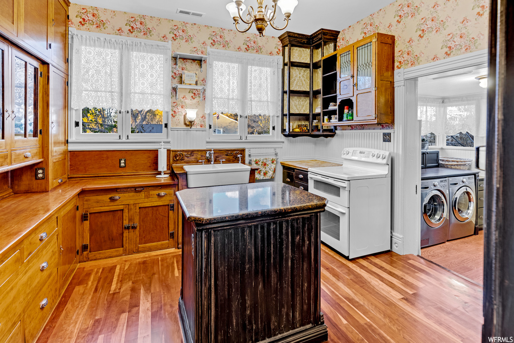Kitchen with a chandelier, a center island, double oven range, independent washer and dryer, and light wood-type flooring