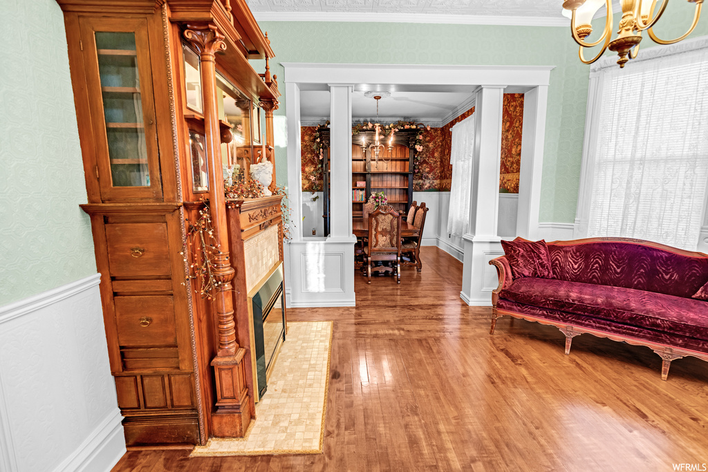 Interior space featuring an inviting chandelier, decorative columns, crown molding, and light hardwood / wood-style floors
