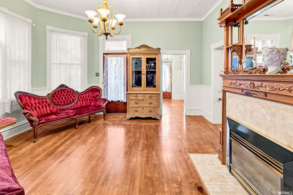Living room featuring light hardwood / wood-style flooring, a wealth of natural light, a fireplace, and crown molding