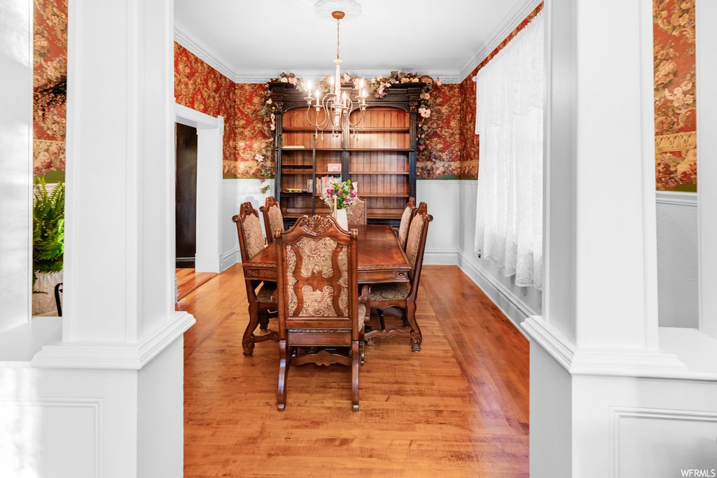 Dining space with light wood-type flooring, an inviting chandelier, and crown molding