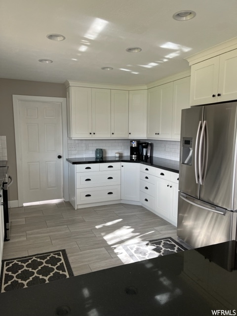 Kitchen featuring light tile floors, white cabinets, stainless steel fridge with ice dispenser, and backsplash