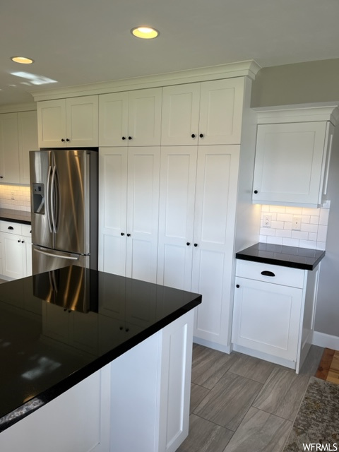 Kitchen with tasteful backsplash, stainless steel fridge with ice dispenser, light hardwood / wood-style floors, and white cabinetry