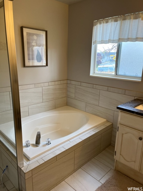 Bathroom with tile floors, tiled tub, and vanity