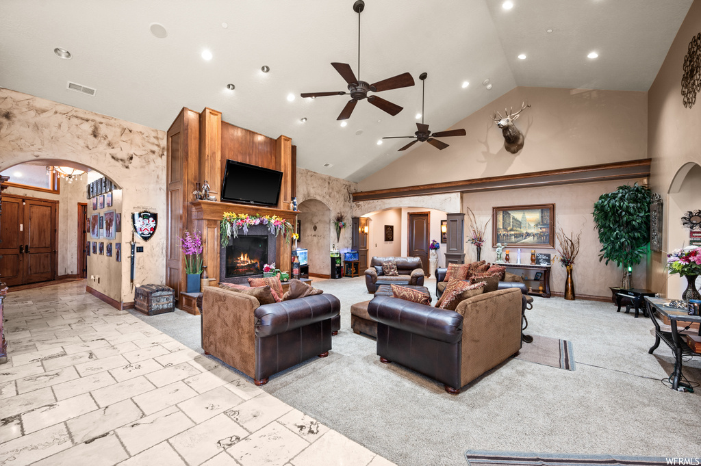 Living room with a large fireplace, ceiling fan, high vaulted ceiling, and light tile flooring