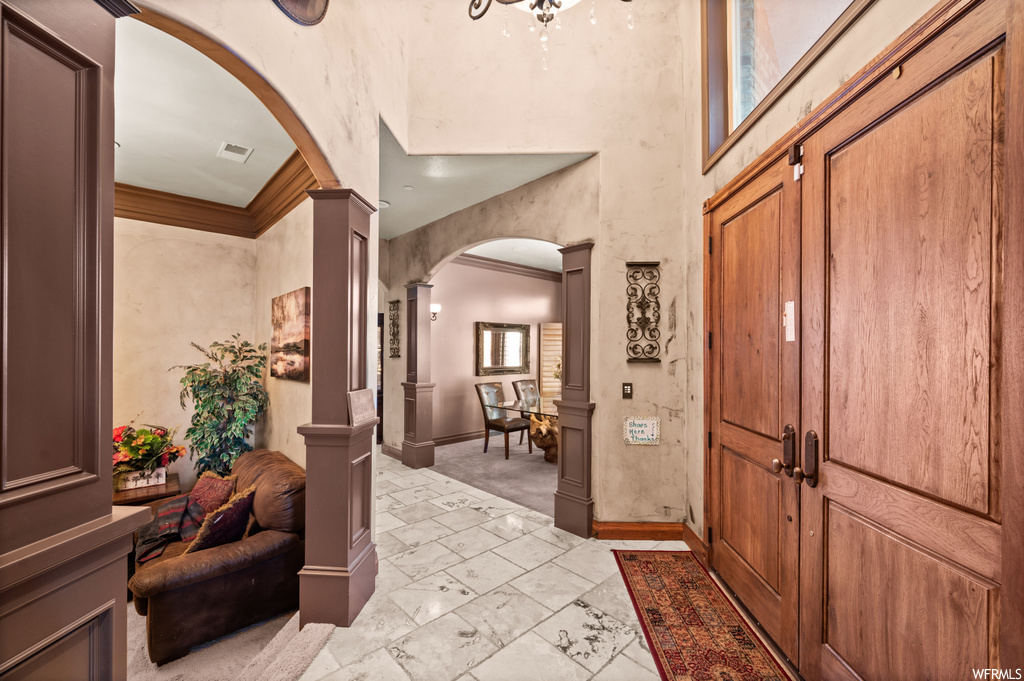 Tiled foyer with ornate columns and ornamental molding