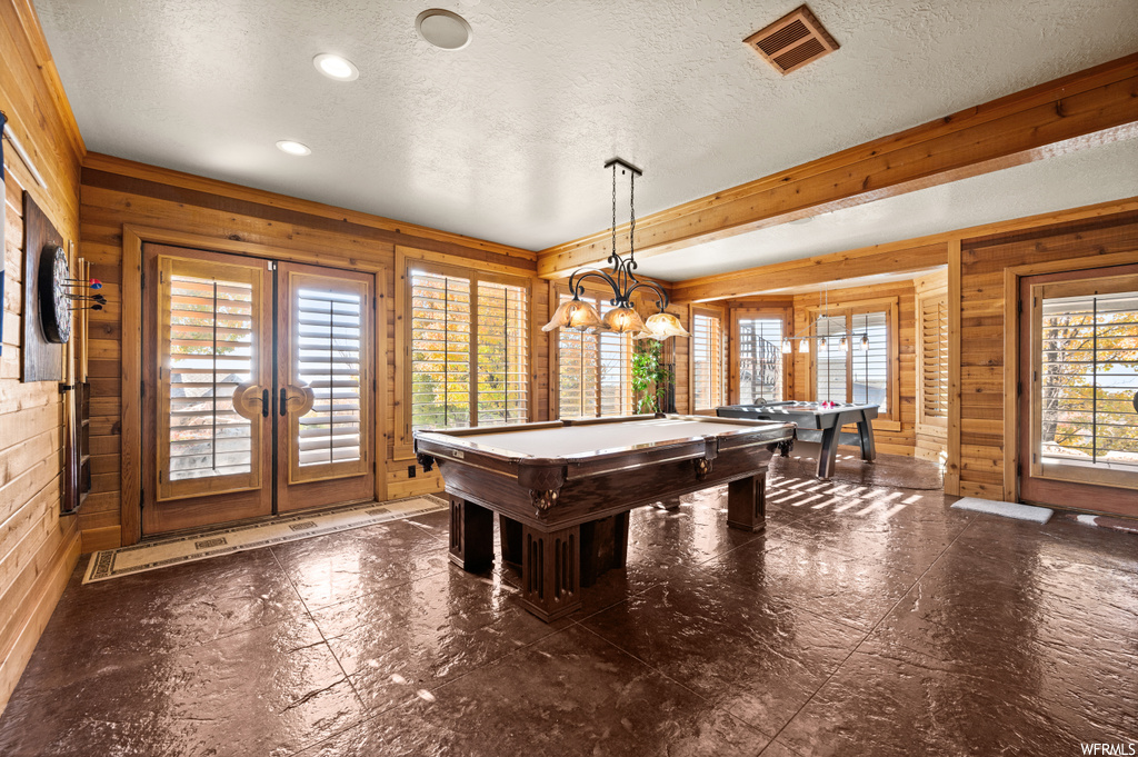 Playroom featuring billiards, a wealth of natural light, wooden walls, and french doors