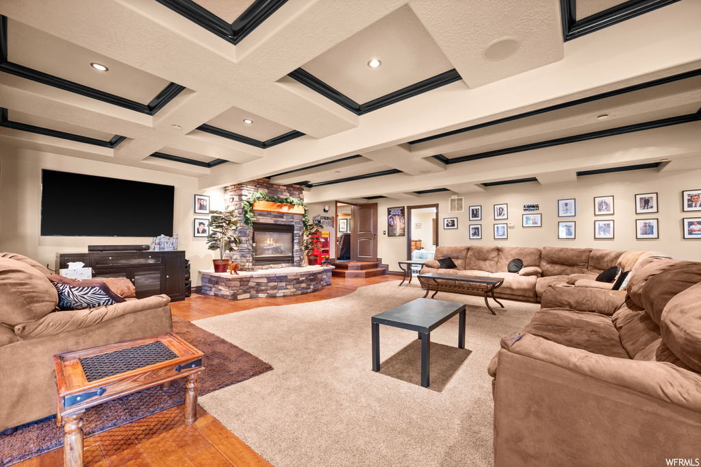 Living room featuring coffered ceiling, beam ceiling, and a stone fireplace