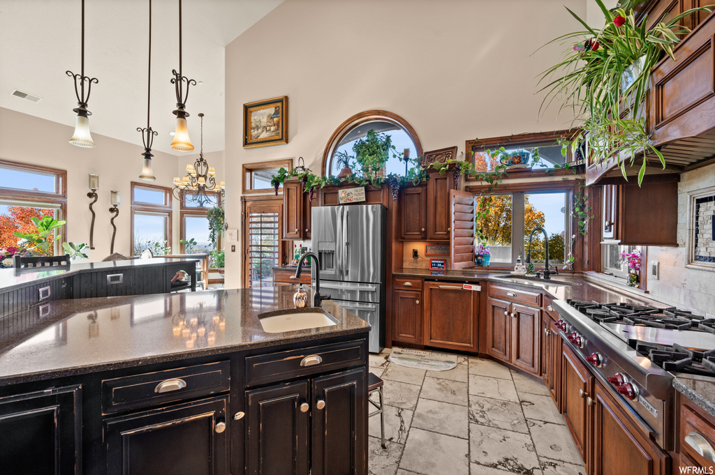 Kitchen with hanging light fixtures, an island with sink, sink, a notable chandelier, and light tile floors