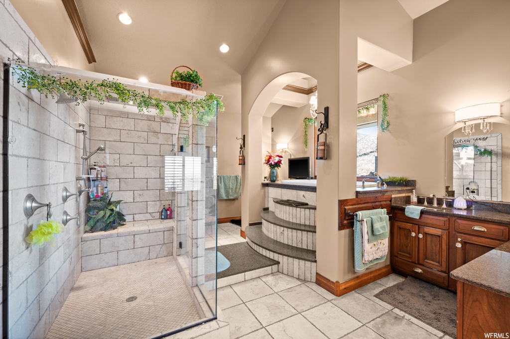 Bathroom with tile flooring, large vanity, plenty of natural light, and a tile shower
