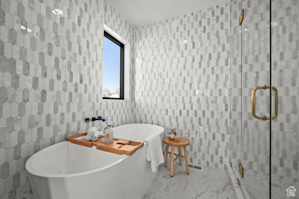 Bathroom featuring tile flooring, shower with separate bathtub, and tile walls
