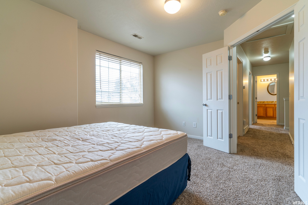 Bedroom with ensuite bathroom, a closet, and light colored carpet