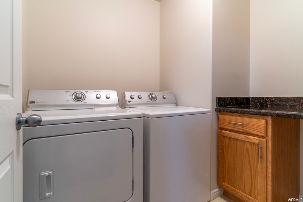 Laundry area featuring washing machine and clothes dryer and cabinets
