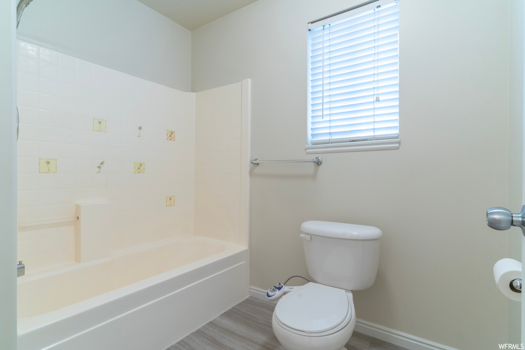 Bathroom featuring toilet, shower / bathing tub combination, and hardwood / wood-style flooring