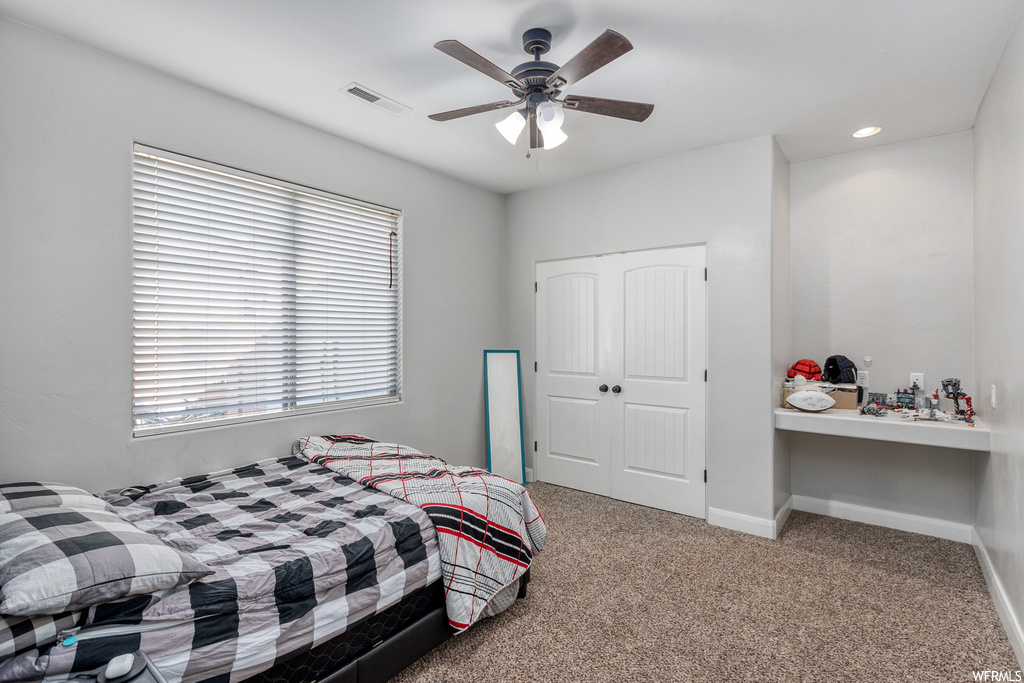 Bedroom with a closet, ceiling fan, and light colored carpet