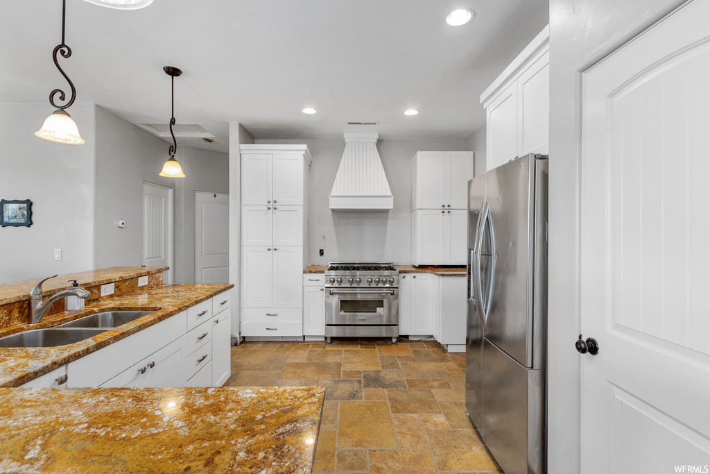 Kitchen with white cabinets, sink, appliances with stainless steel finishes, and decorative light fixtures