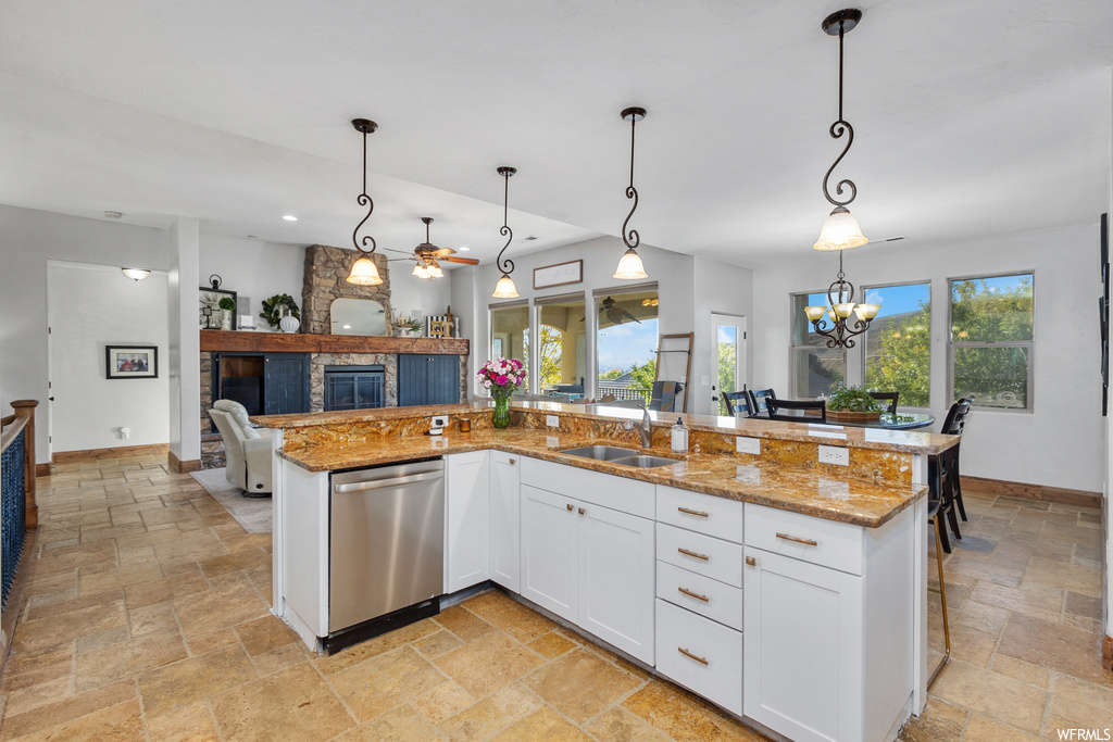 Kitchen featuring stainless steel dishwasher, a wealth of natural light, decorative light fixtures, and white cabinets