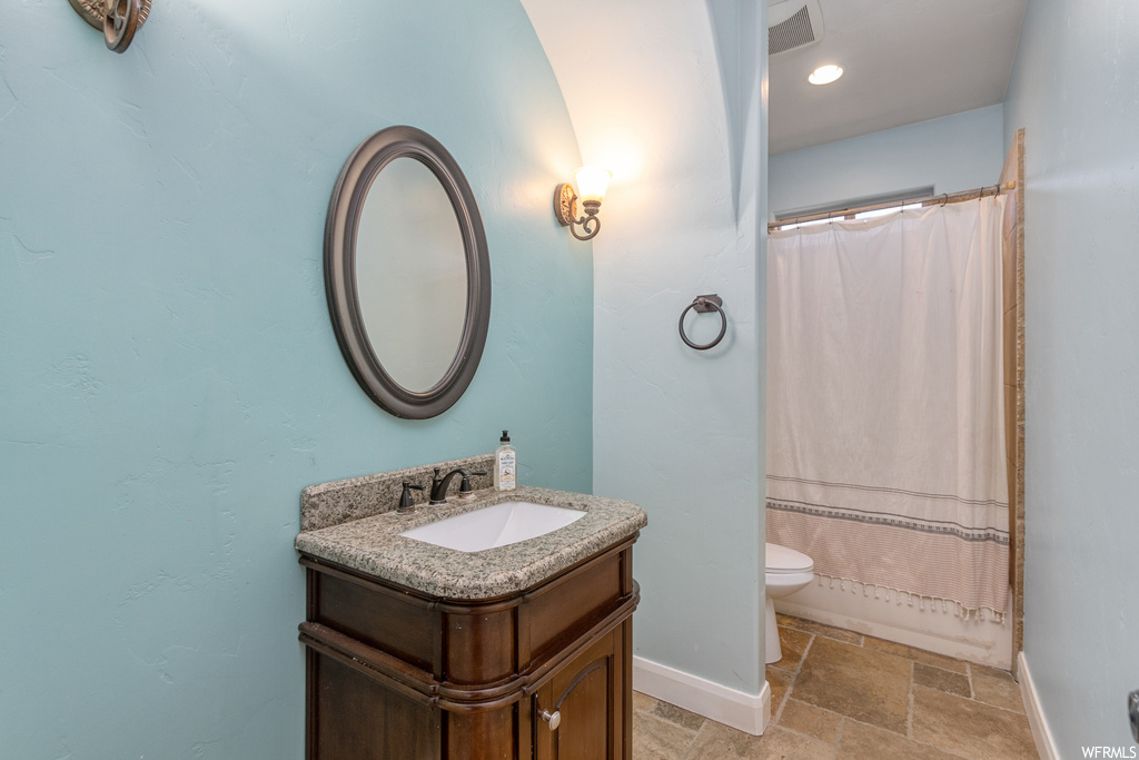 Bathroom featuring toilet, oversized vanity, and tile flooring
