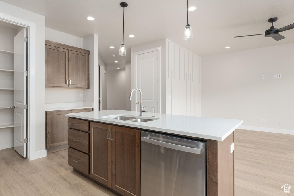 Kitchen with light hardwood / wood-style floors, stainless steel dishwasher, and an island with sink