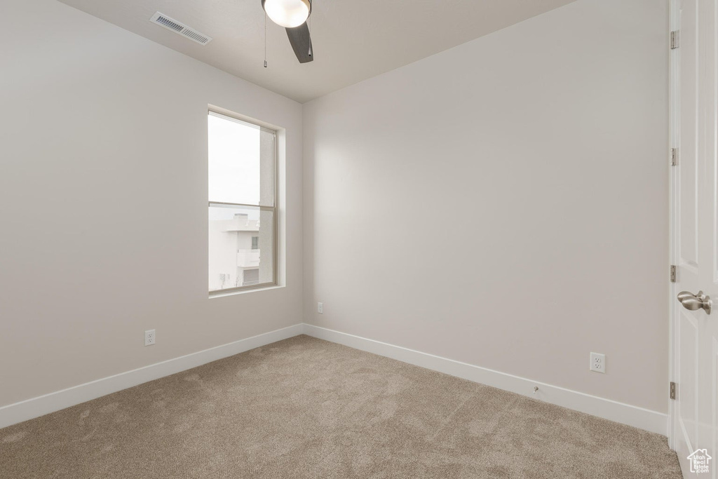 Spare room featuring light carpet and ceiling fan