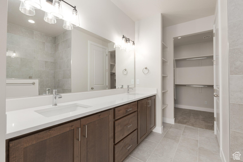 Bathroom with a chandelier, tile patterned flooring, and double sink vanity