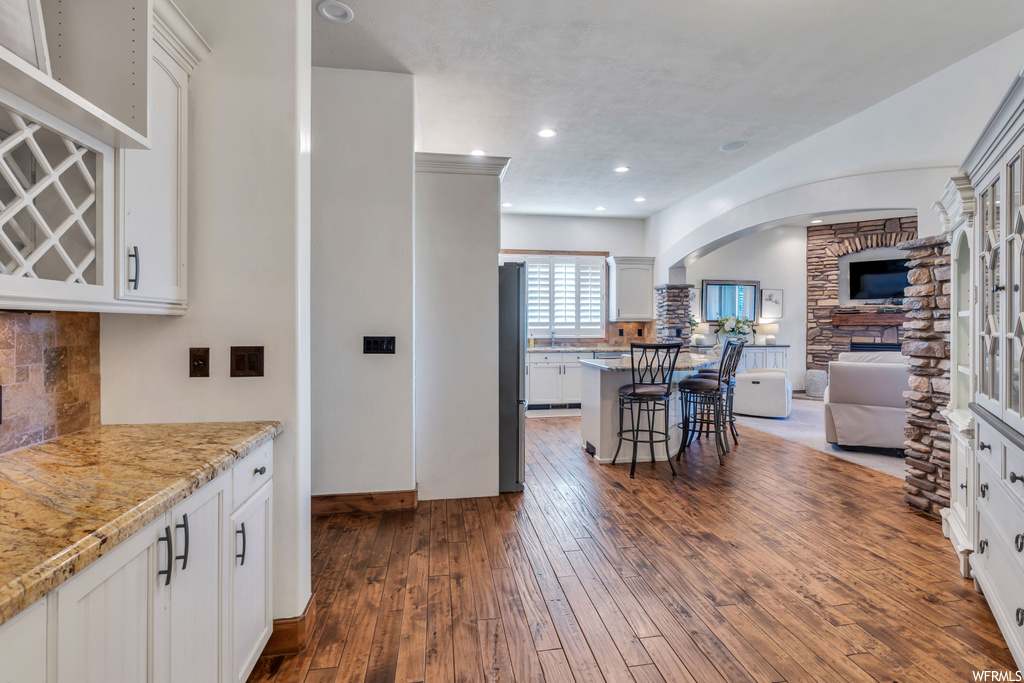 Kitchen featuring a fireplace, dark hardwood / wood-style flooring, white cabinetry, and a kitchen breakfast bar