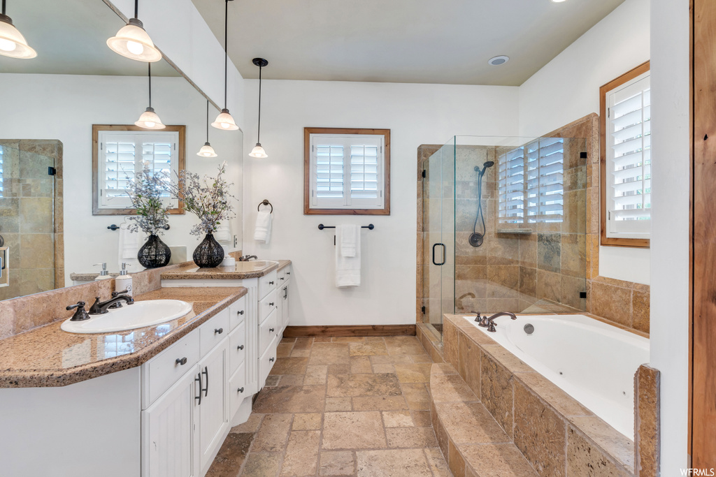 Bathroom featuring a wealth of natural light, tile floors, shower with separate bathtub, and dual bowl vanity