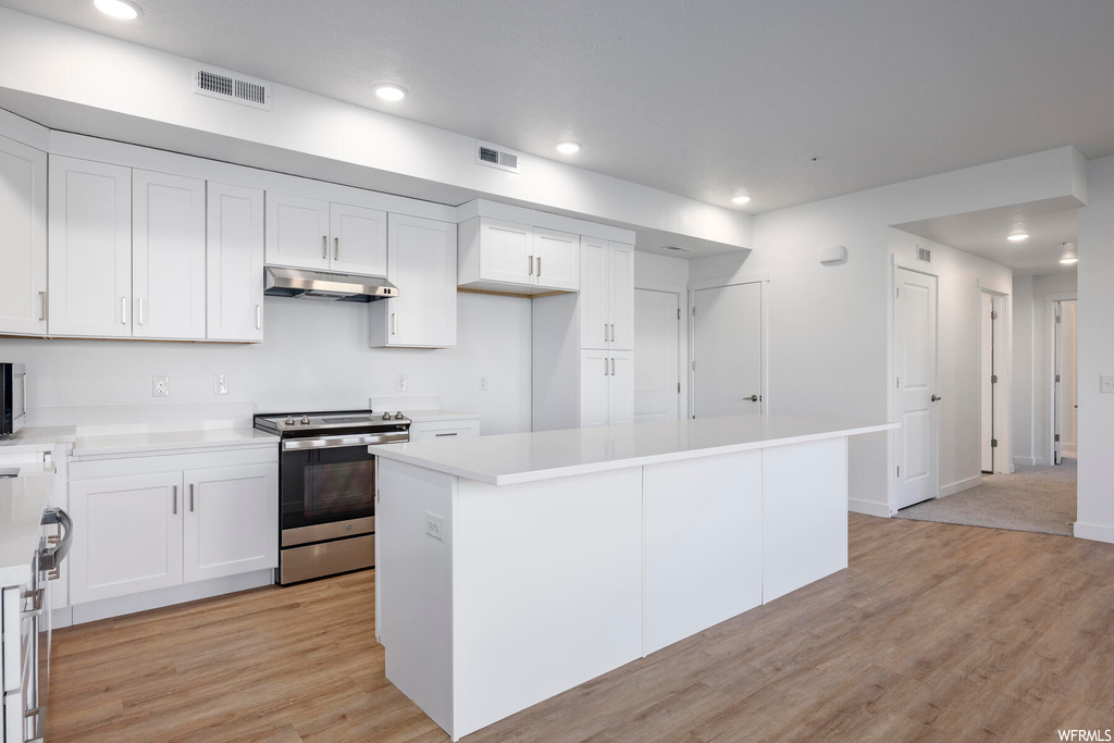 Kitchen featuring a center island, white cabinets, stainless steel appliances, and light hardwood / wood-style floors