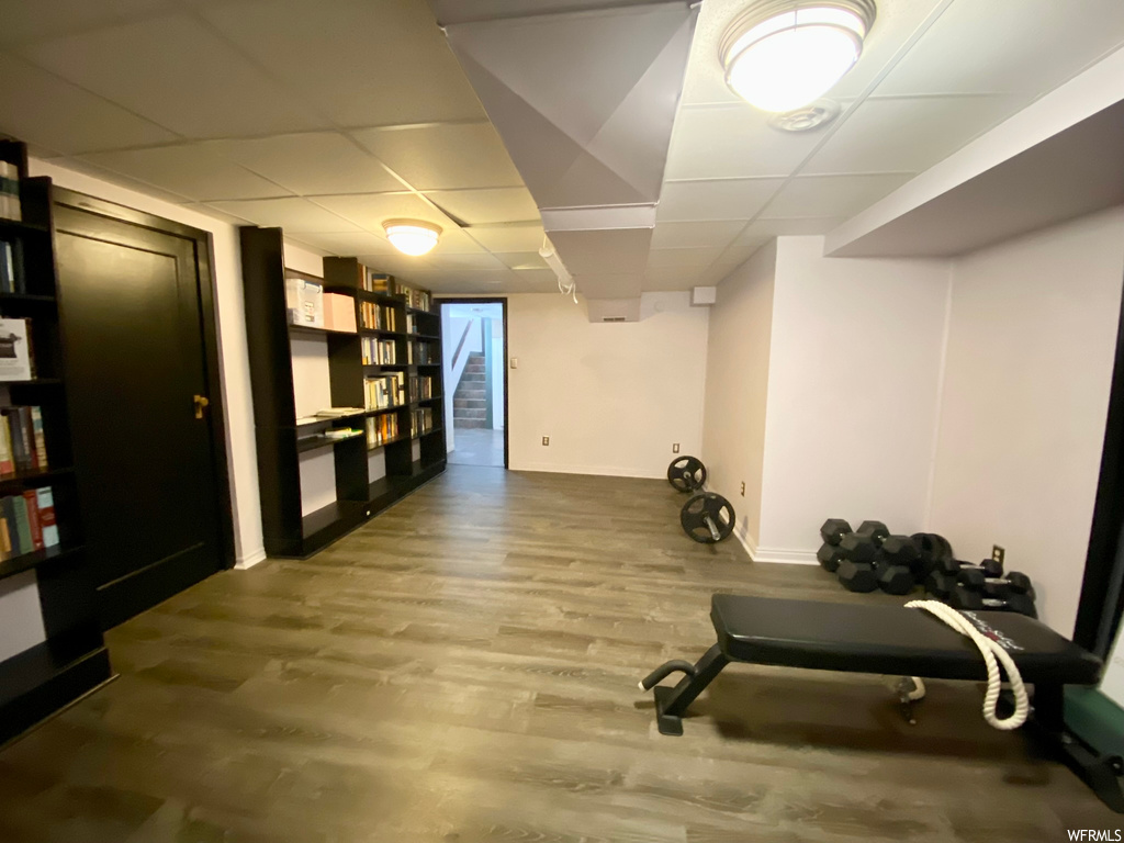 Exercise area with a paneled ceiling and hardwood / wood-style flooring