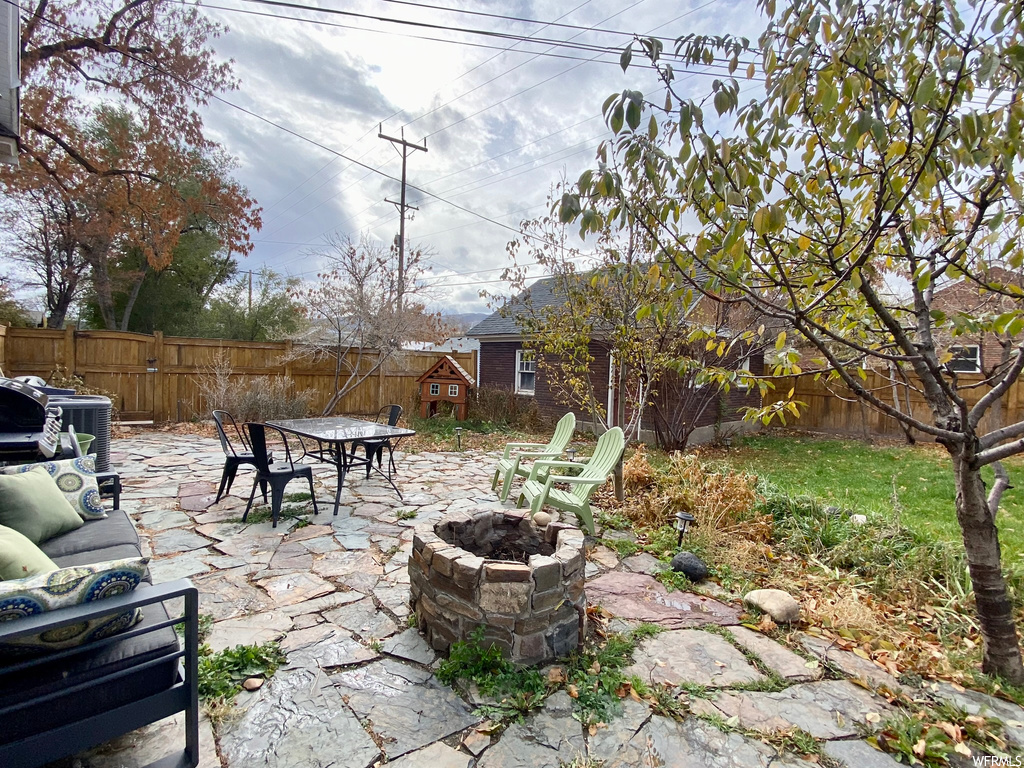 View of patio with a shed and an outdoor fire pit