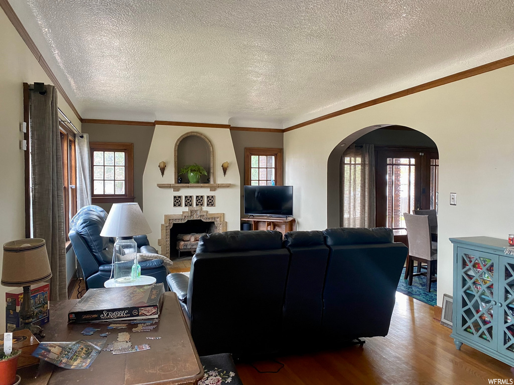 Living room featuring crown molding, a textured ceiling, and hardwood / wood-style flooring