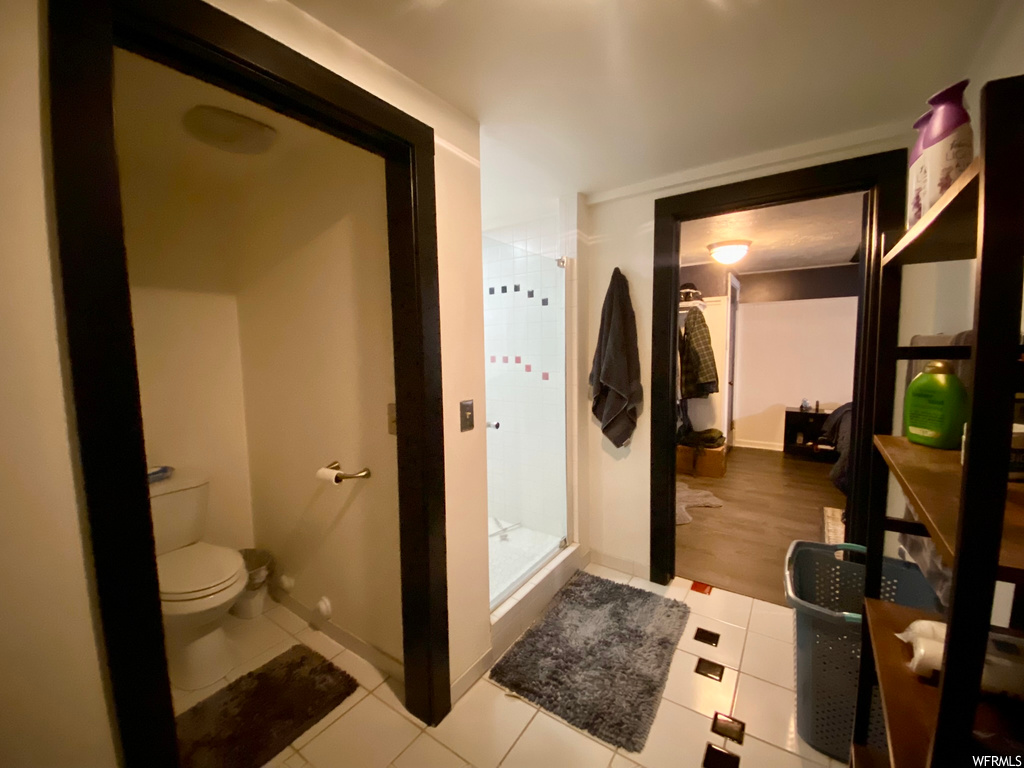 Bathroom with toilet, tile flooring, and an enclosed shower