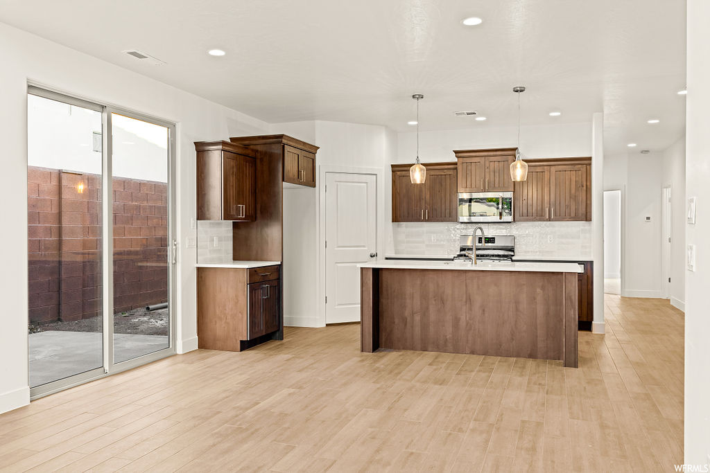 Kitchen with pendant lighting, a center island with sink, a healthy amount of sunlight, and tasteful backsplash