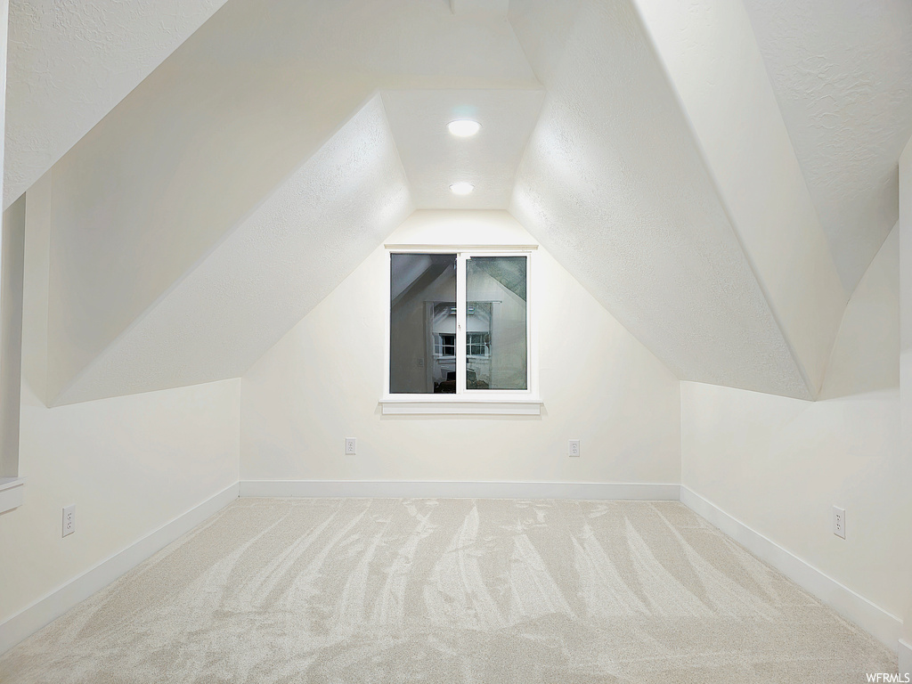 Bonus room with lofted ceiling and light carpet