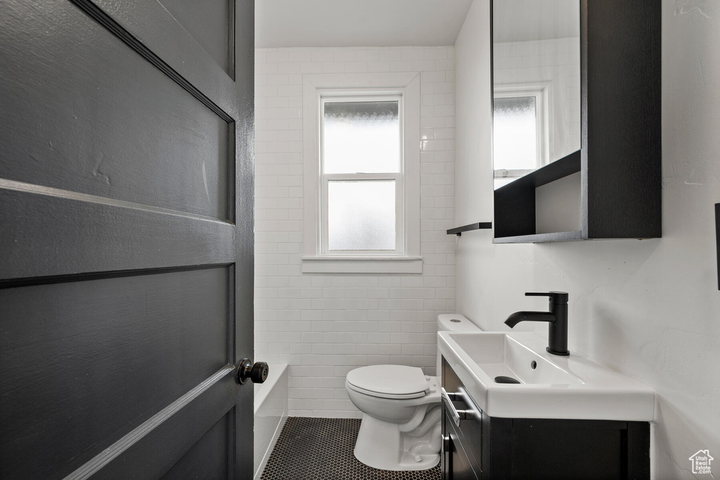 Full bathroom featuring shower / washtub combination, oversized vanity, tile walls, toilet, and tile flooring