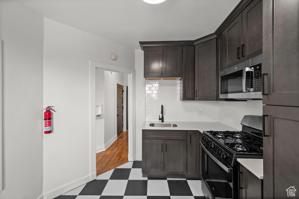 Kitchen featuring dark hardwood / wood-style flooring, dark brown cabinets, stainless steel appliances, tasteful backsplash, and sink